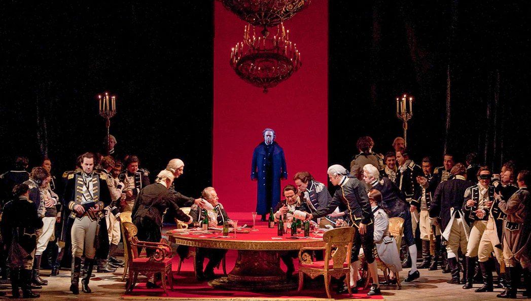 Opera scene from "The Queen of Spades" with actors in period costumes around a table.