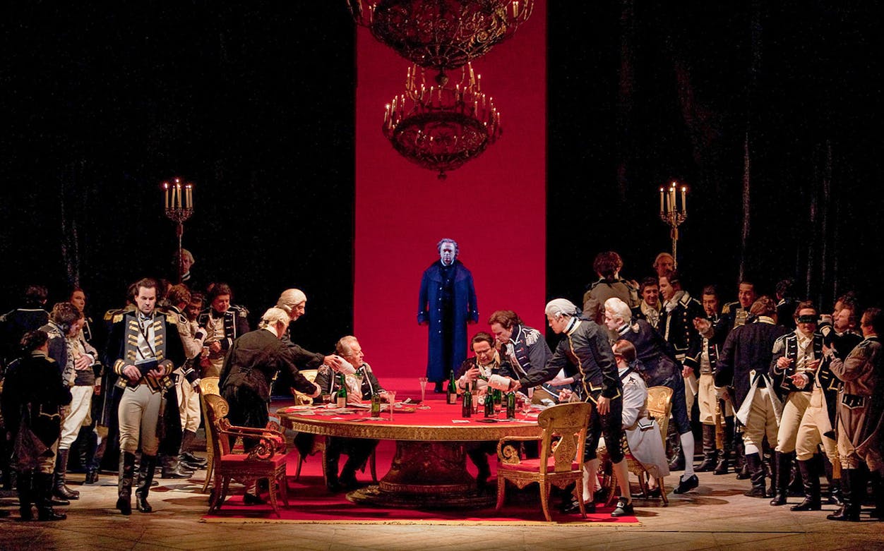 Opera scene from "The Queen of Spades" with actors in period costumes around a table.