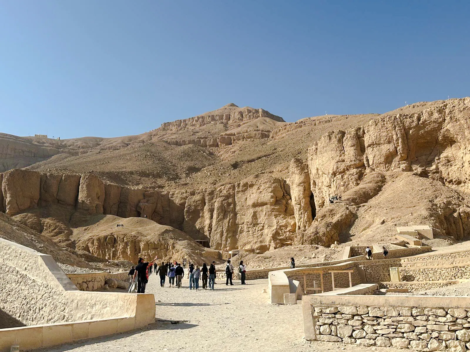 Tourists exploring the Valley of the Kings, Luxor, Egypt, surrounded by ancient rock formations.