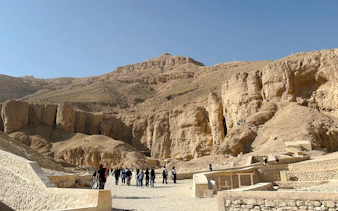 Tourists exploring the Valley of the Kings, Luxor, Egypt, surrounded by ancient rock formations.