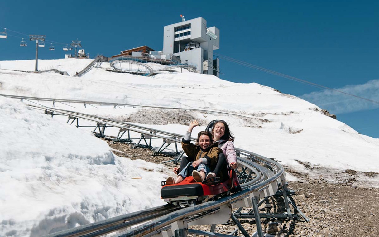 Alpine coaster ride at Glacier 3000, Les Diablerets, Switzerland with snowy mountain backdrop.