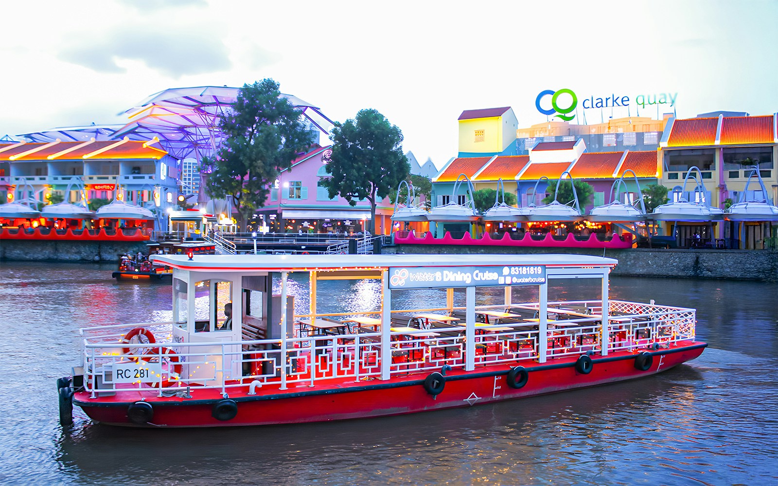 Singapore River Cruise boat on water with city skyline in the background.