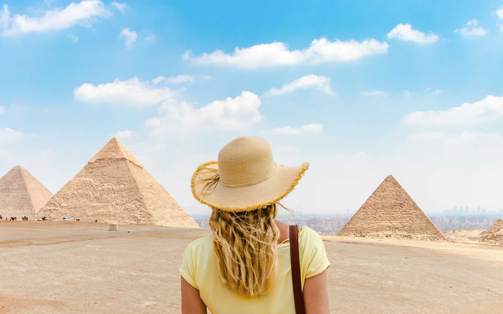Tourist facing Giza Pyramids in Egypt under a clear sky.