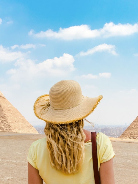 Tourist facing Giza Pyramids in Egypt under a clear sky.