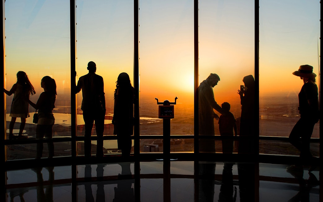 Visitors enjoying sunrise view from Burj Khalifa Level 124 observation deck.