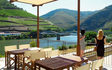 Tourists enjoying the view of Douro Valley vineyards and river from a terrace.
