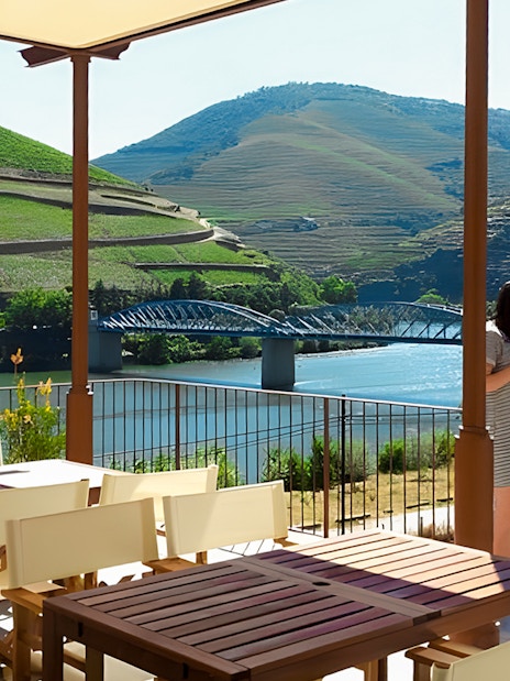 Tourists enjoying the view of Douro Valley vineyards and river from a terrace.