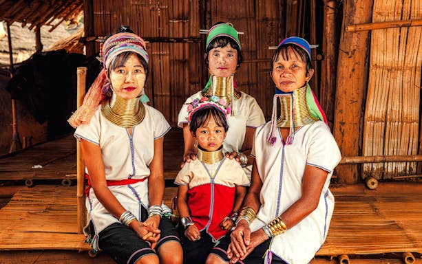 Women and child in traditional attire with neck rings, Karen Long Neck Village, Chiang Rai, Thailand.
