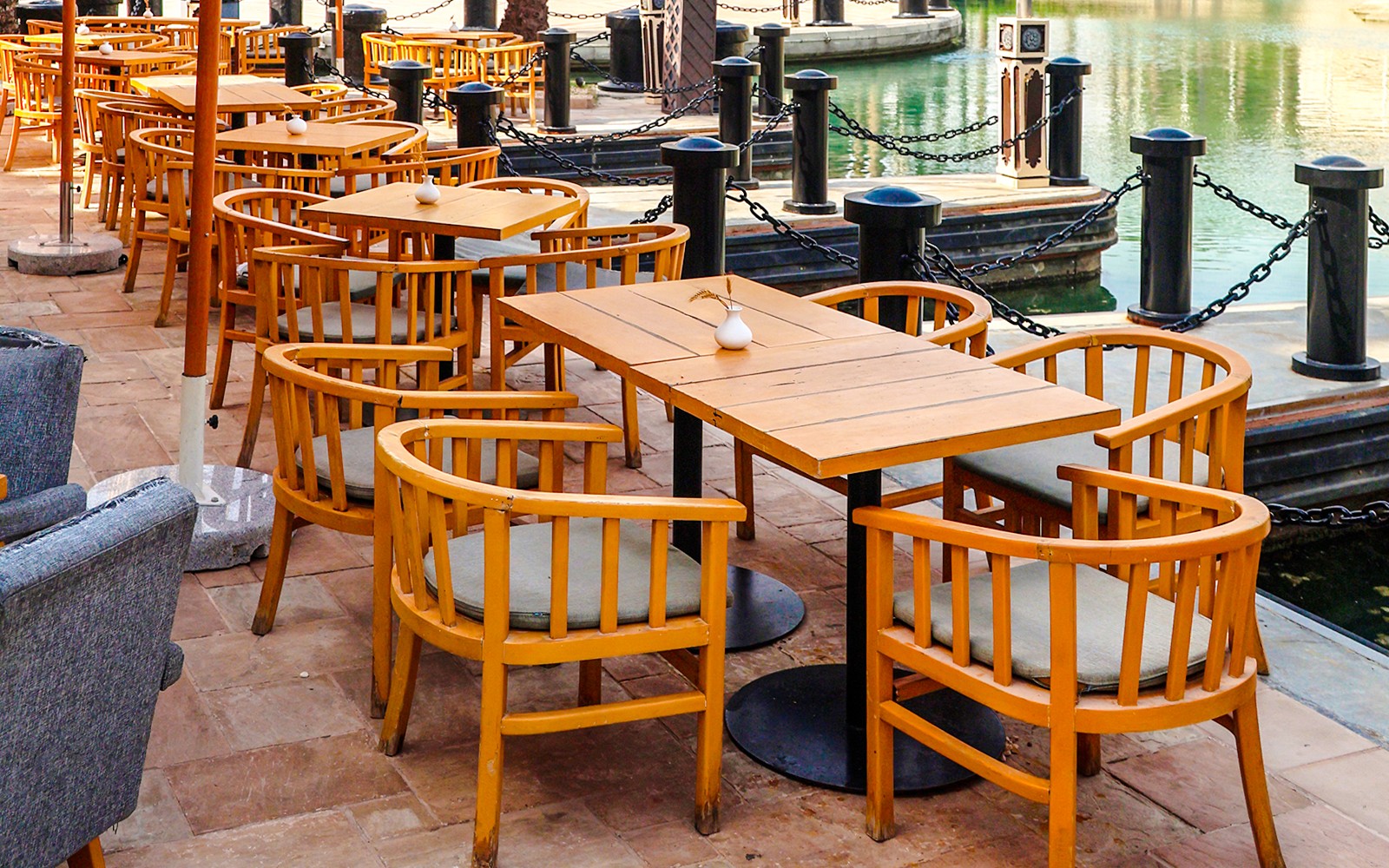 Cafe tables and chairs by a city water channel.