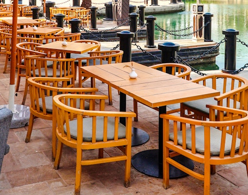 Cafe tables and chairs by a city water channel.