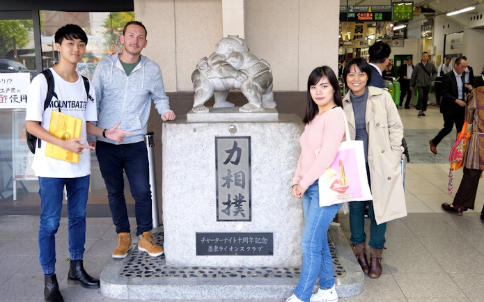 Group posing by sumo statue at Ryogoku Station, Tokyo.