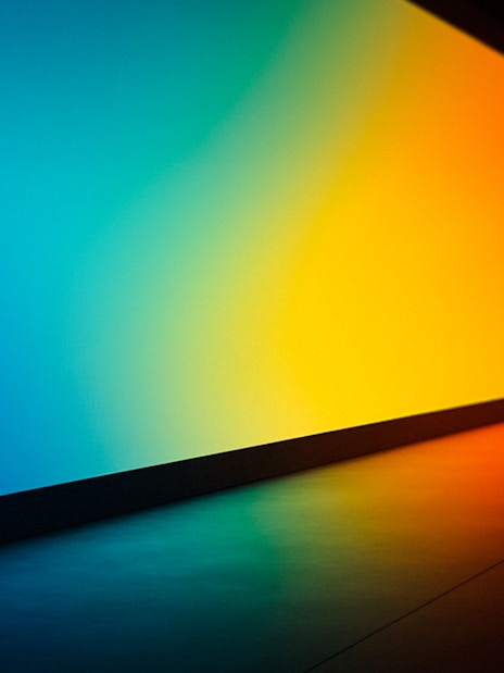 Person observing a large, colorful digital display in a futuristic gallery.