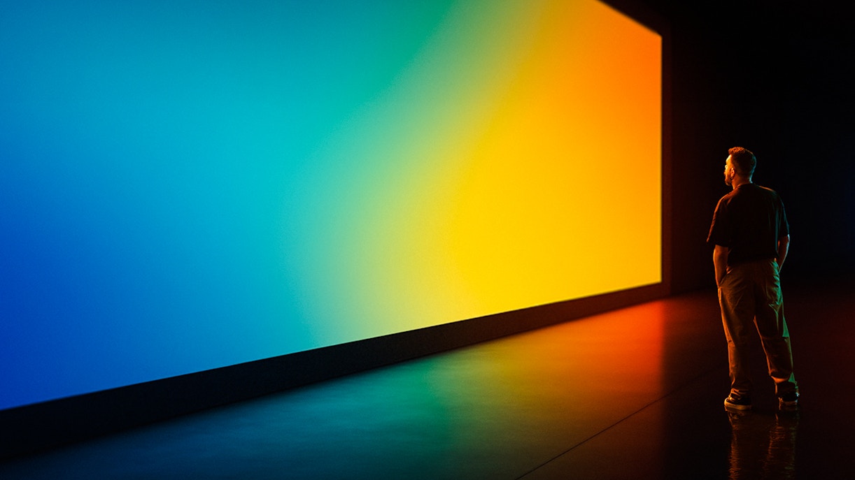 Person observing a large, colorful digital display in a futuristic gallery.