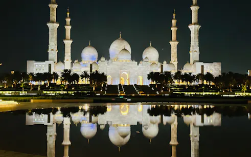 Sheikh Zayed Grand Mosque illuminated at night, reflected in water, Abu Dhabi.