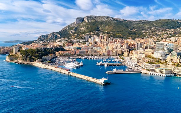 Monaco harbor with yachts and cityscape, view from a boat tour.