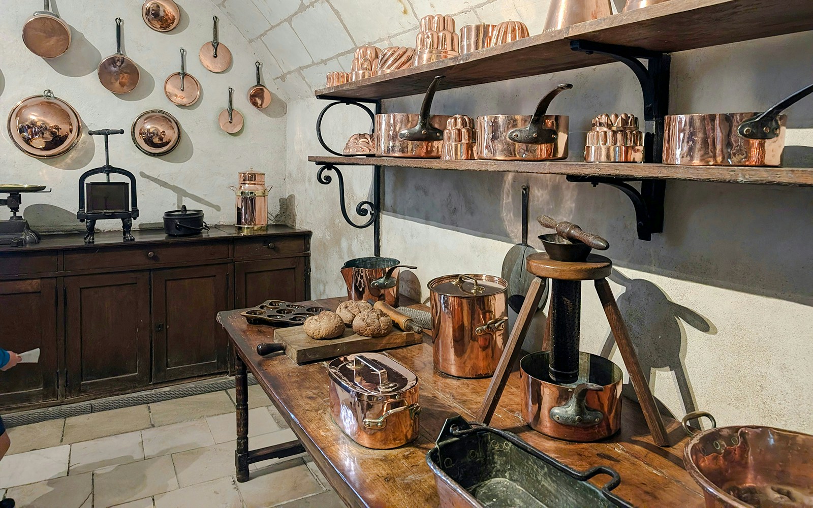 Copper cookware and baking tools in the historic kitchen of Chenonceau Castle, France.