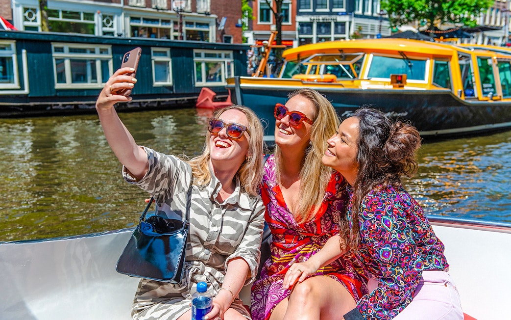 Three people taking a selfie on an Amsterdam canal cruise boat.
