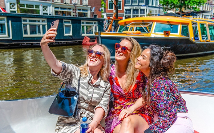 Three people taking a selfie on an Amsterdam canal cruise boat.