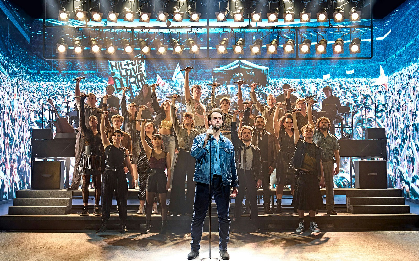 Group performance on stage at Just for One Day event.