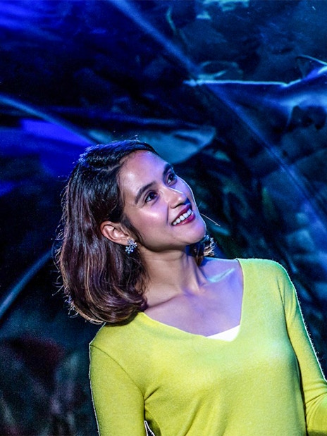 Visitor observing a shark in the tunnel at Aquaria KLCC, Kuala Lumpur.