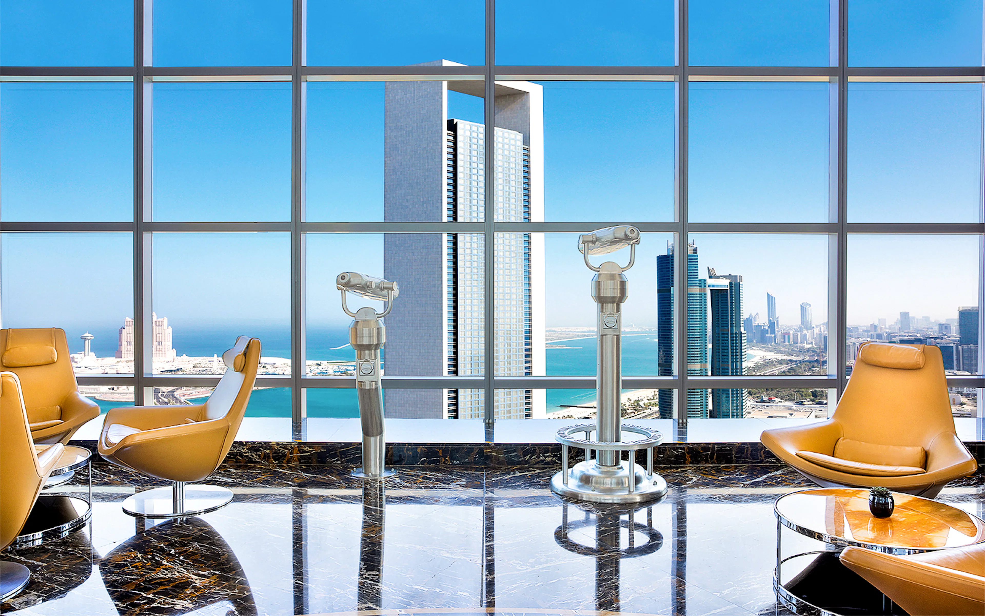 Observation deck view of Abu Dhabi skyline from Etihad Towers with telescopes and seating.