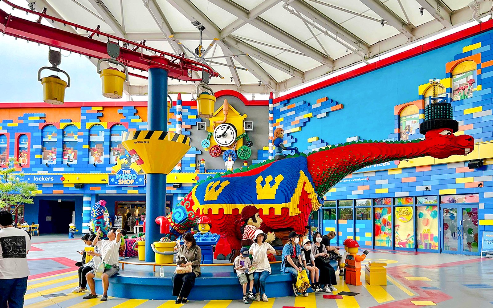 Colorful LEGO dinosaur sculpture at Legoland Japan with visitors seated nearby.