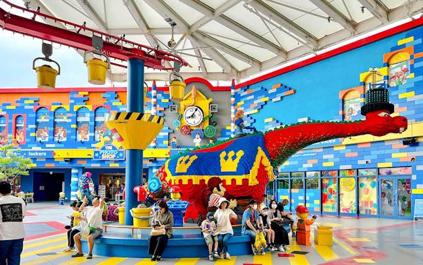 Colorful LEGO dinosaur sculpture at Legoland Japan with visitors seated nearby.