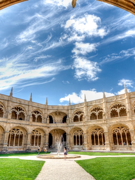 Cloister of Jeronimos Monastery in Lisbon with ornate arches and central fountain.