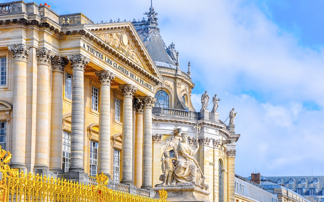 Palace of Versailles facade with statues and ornate architecture, France.