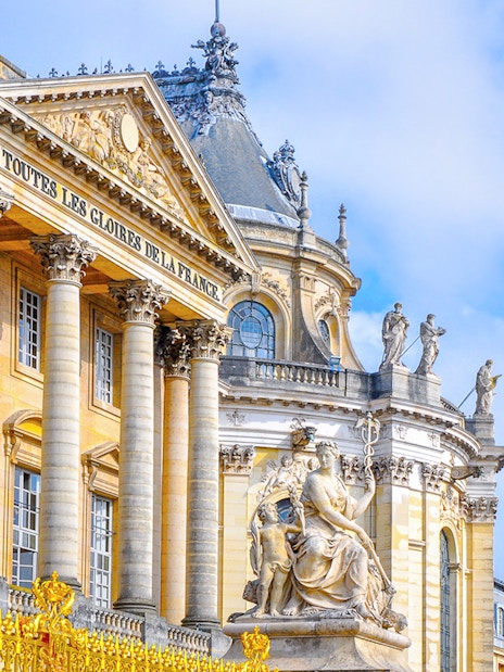 Palace of Versailles facade with statues and ornate architecture, France.