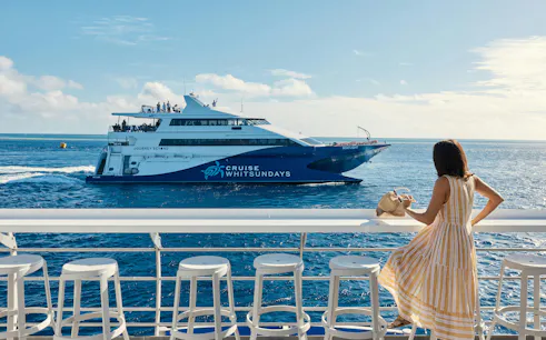 Cruise ship on Whitsundays Island tour with passenger enjoying ocean view.