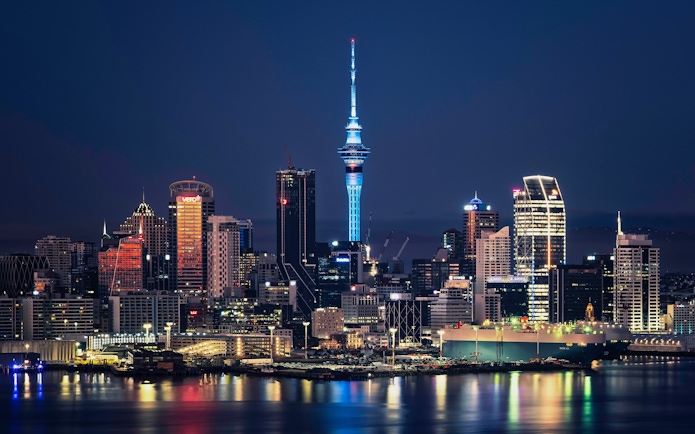 Auckland city skyline with Sky Tower illuminated at night, New Zealand.