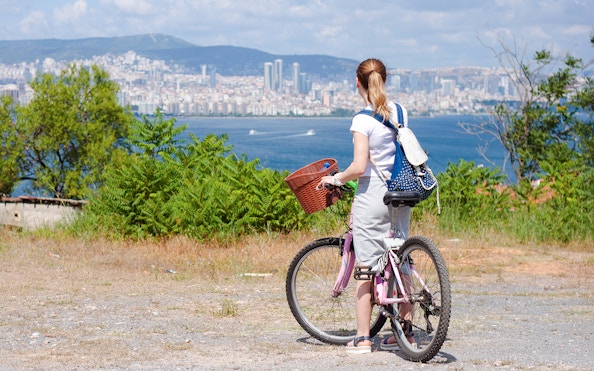 Woman biking on Prince Island with Istanbul skyline in background.