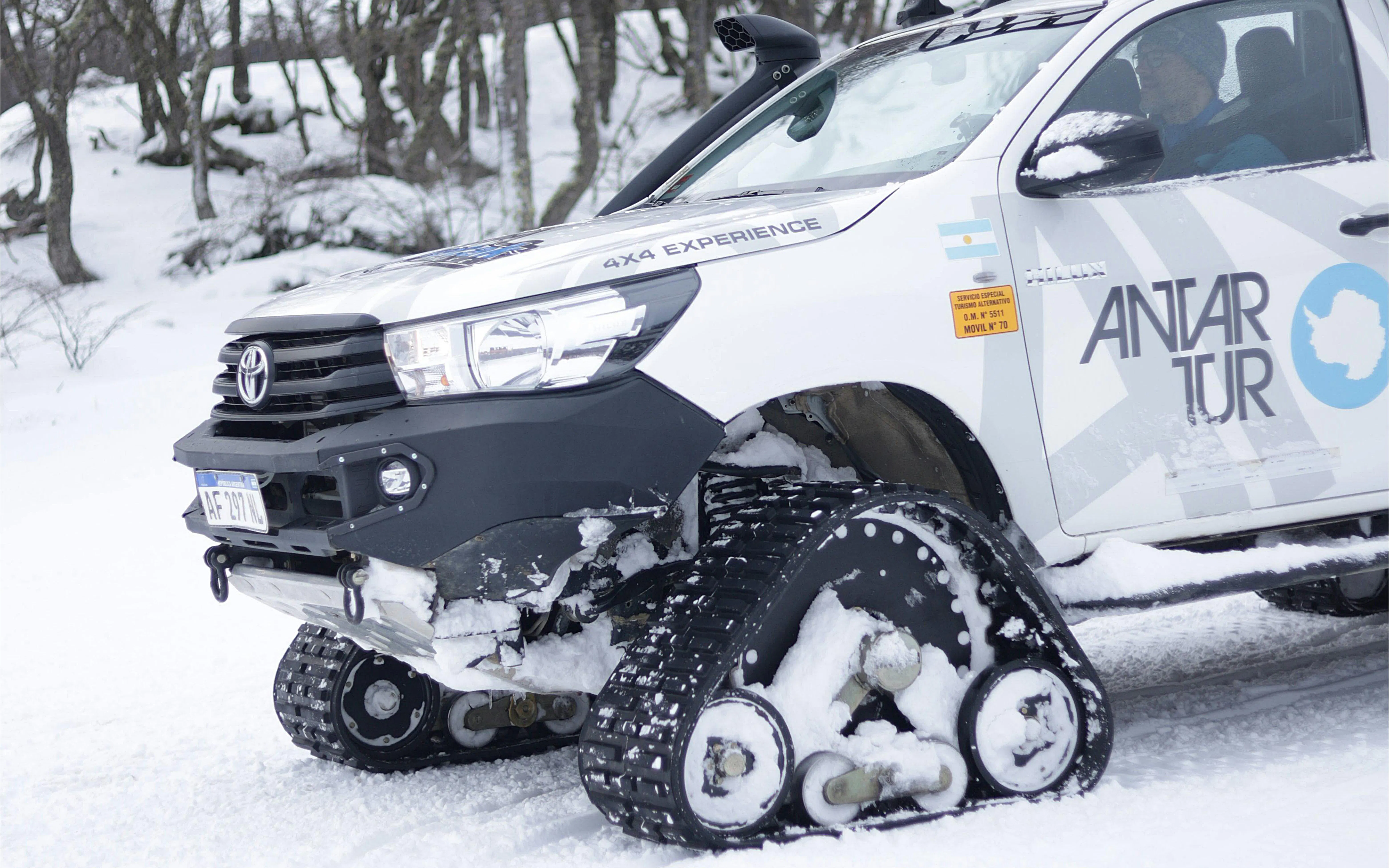 Snow vehicle with tracks in a snowy forest during Snow and Fire Night experience.