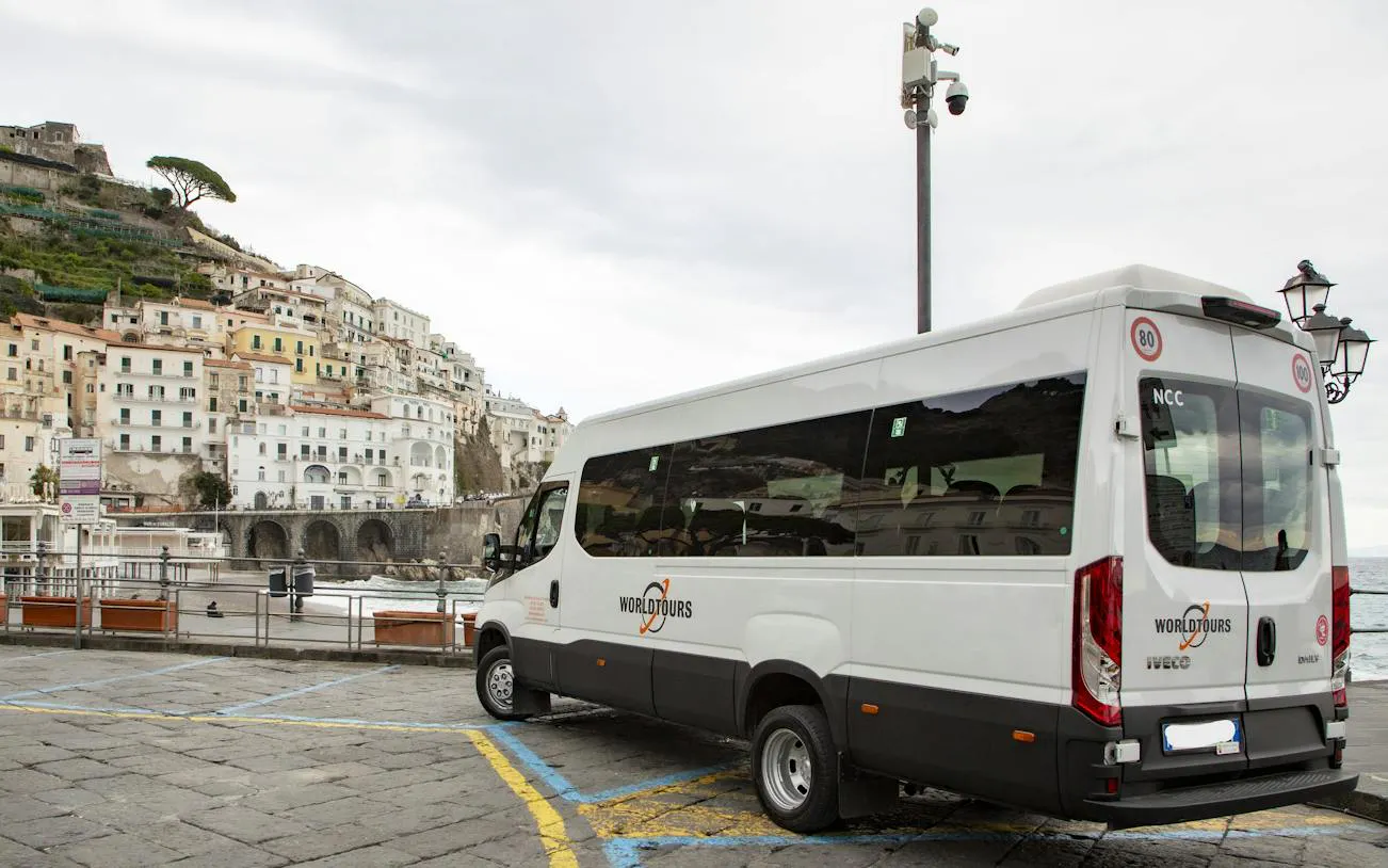 Tour van parked in Amalfi with coastal town view in background.
