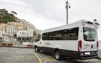 Tour van parked in Amalfi with coastal town view in background.