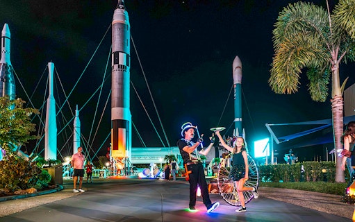Performer and child with glowing props at Kennedy Space Center after-hours event.