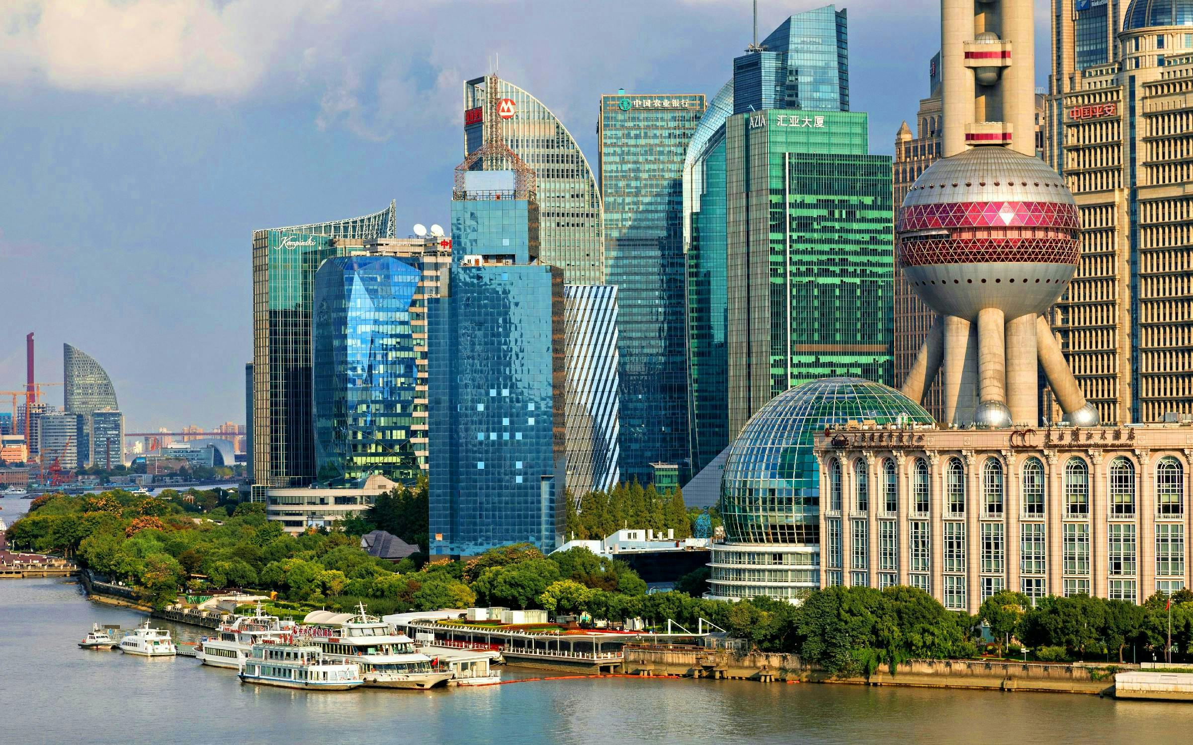 Cruise ships on Huangpu River with Shanghai skyline, including Oriental Pearl Tower.