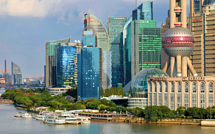Cruise ships on Huangpu River with Shanghai skyline, including Oriental Pearl Tower.
