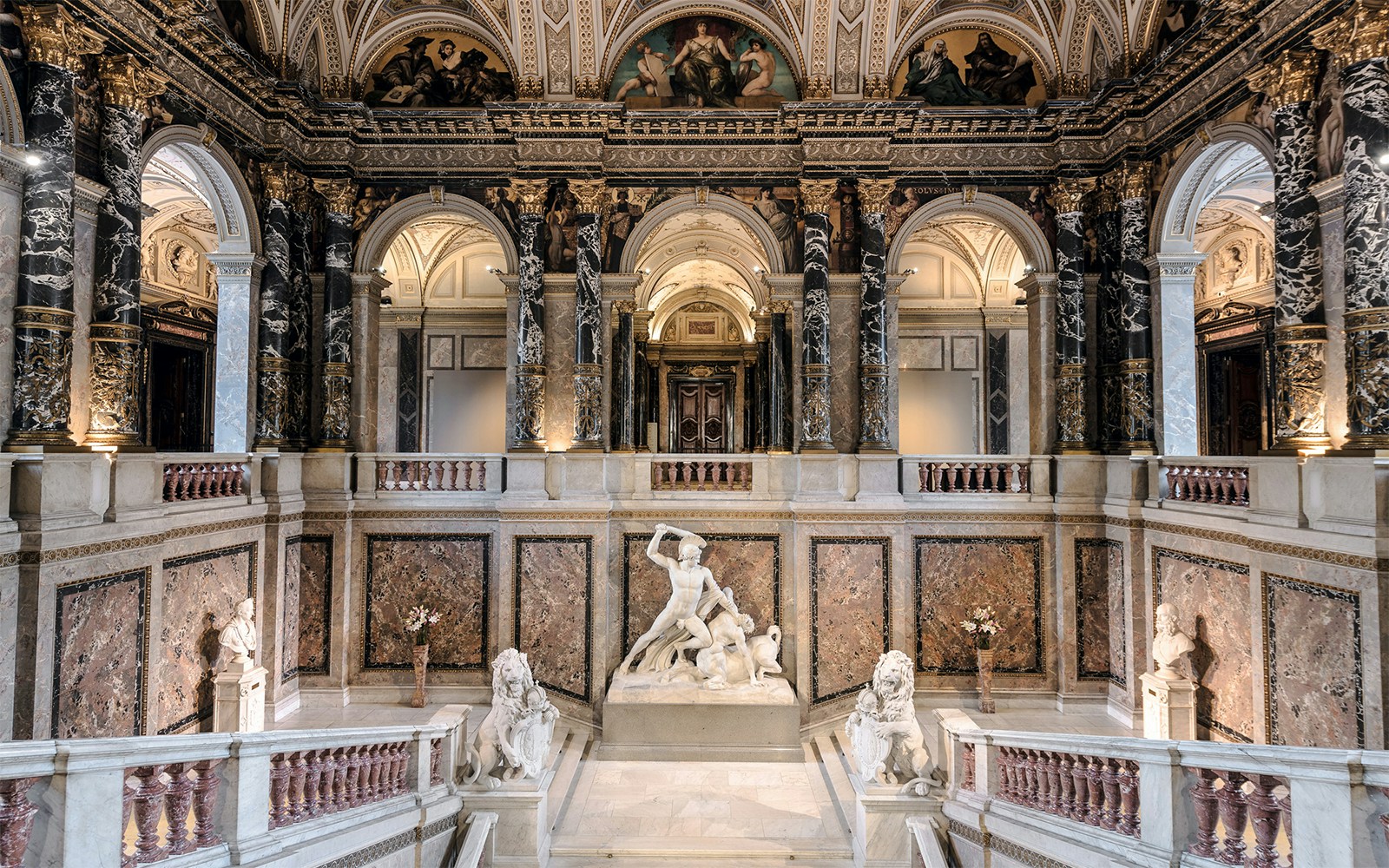 Kunsthistorisches Museum interior with grand staircase and marble sculptures.