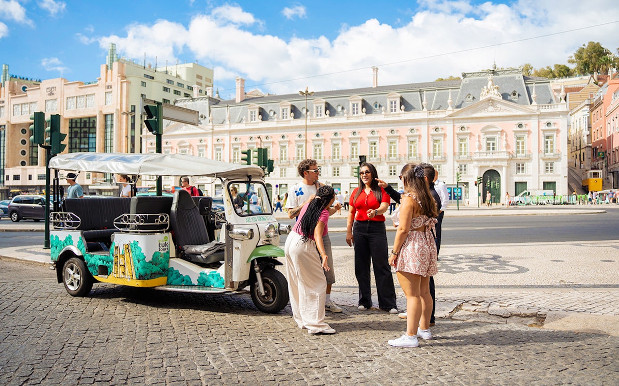 Tourists with guide at scenic Lisbon spot during eco tuk tuk tour.