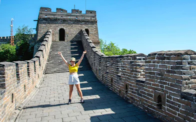 Visitor on Mutianyu section of the Great Wall of China near Beijing, standing on the ancient stone pathway.