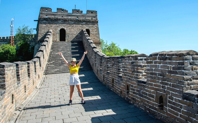 Visitor on Mutianyu section of the Great Wall of China near Beijing, standing on the ancient stone pathway.