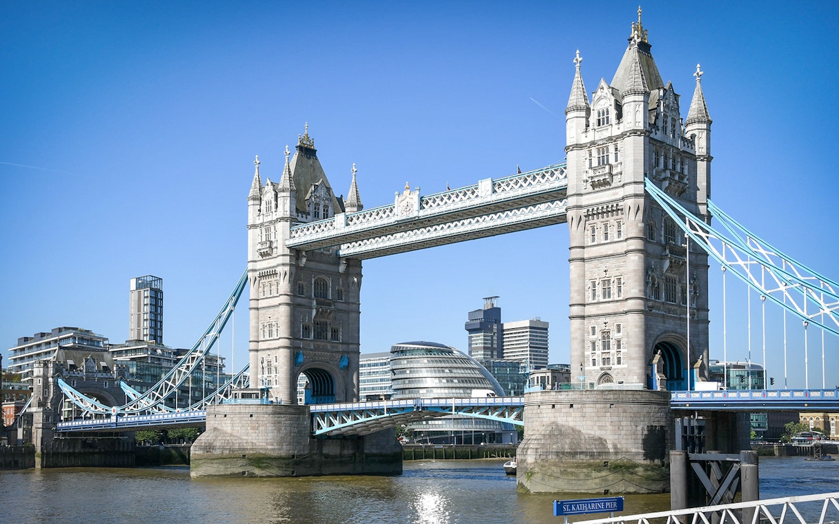 Tower Bridge spanning the River Thames in London with modern buildings in the background.