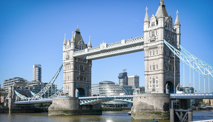 Tower Bridge spanning the River Thames in London with modern buildings in the background.
