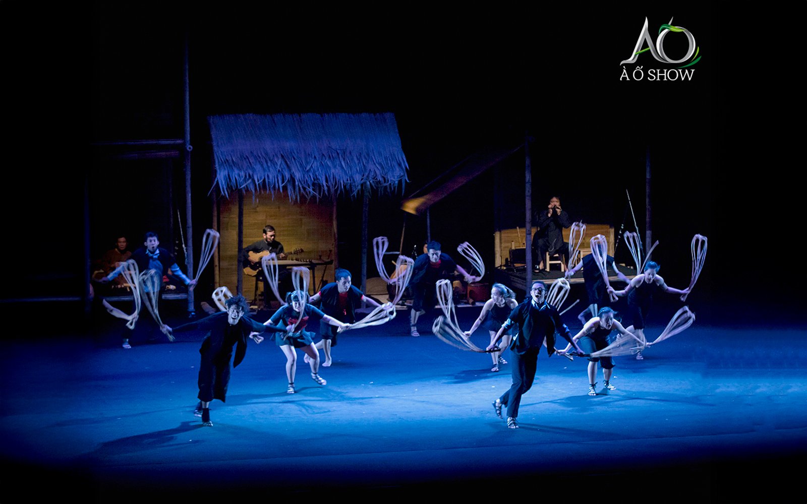 Performers at AO Show depicting traditional village life with bamboo props.