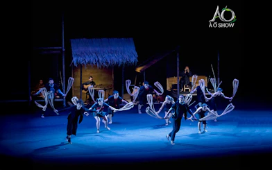 Performers at AO Show depicting traditional village life with bamboo props.