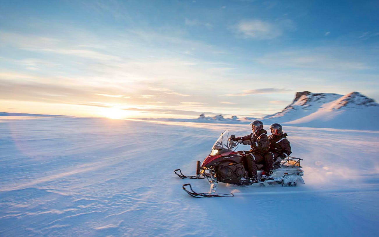 Snowmobiling on a glacier during Secret Lagoon hot spring tour in Iceland.