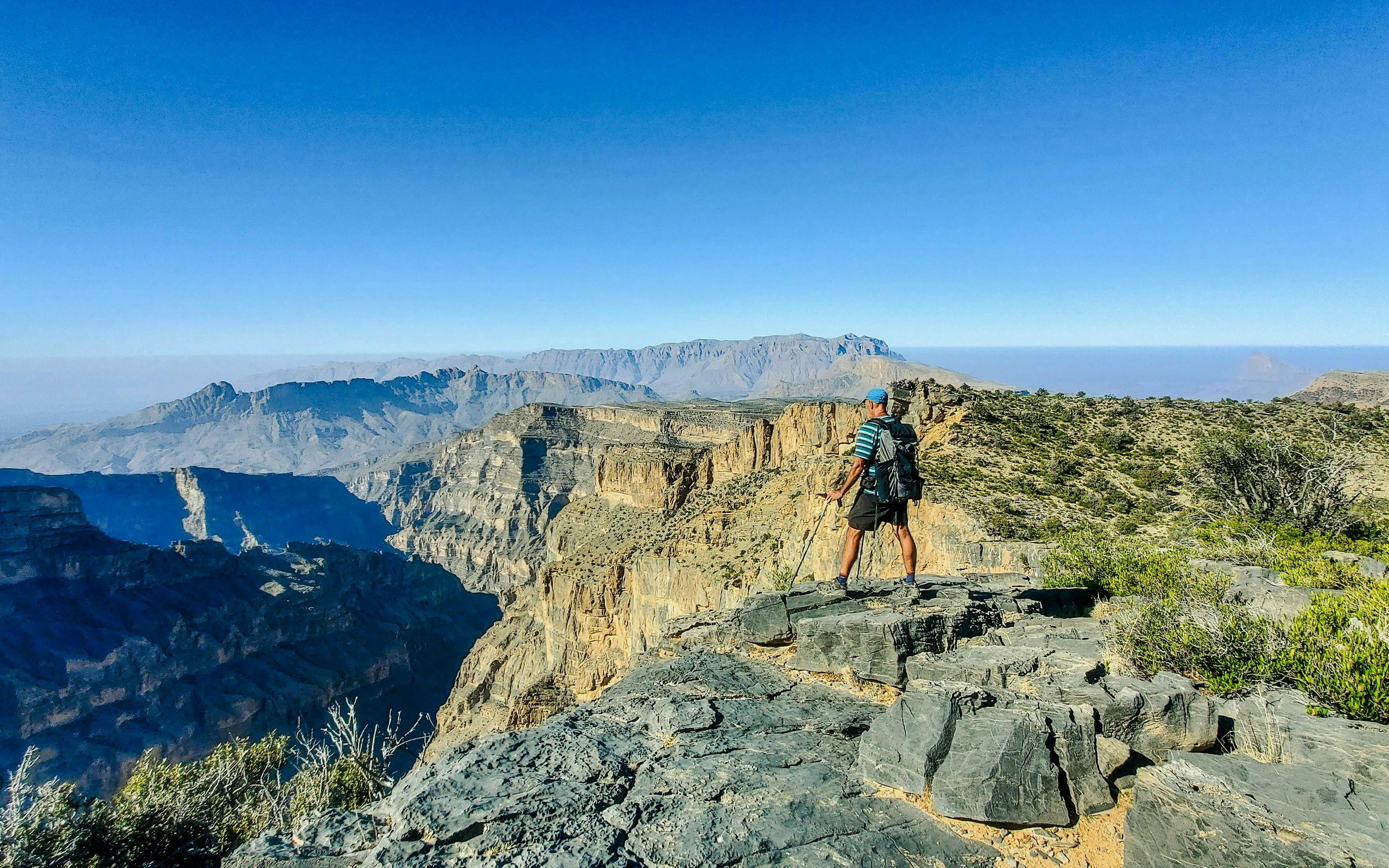 Hiker overlooking Jebel Shams and Wadi Nakhr, the Grand Canyon of Oman, Al Hamra, Oman.