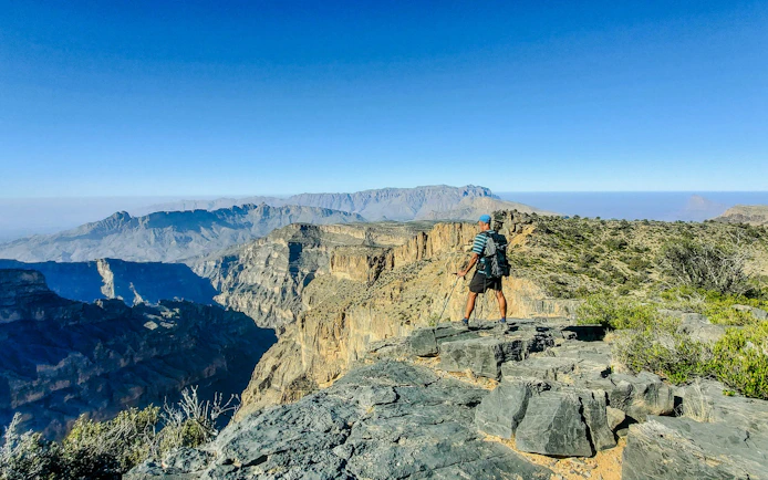 Hiker overlooking Jebel Shams and Wadi Nakhr, the Grand Canyon of Oman, Al Hamra, Oman.